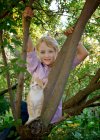 Kleiner blonder Junge im Baum mit einem Kätzchen auf dem Land. — Stockfoto