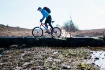 Человек катается на велосипеде по грязной луже в то время как горный велосипед в Англии — стоковое фото