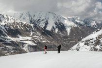 Мужские друзья со сплитбордами на снежном поле против горного хребта во время отпуска — стоковое фото