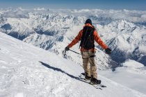 Vista trasera del hombre de pie con los brazos extendidos en la montaña nevada durante las vacaciones - foto de stock