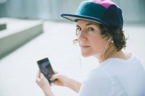 Жінка в кепці слухає музику з навушниками — стокове фото