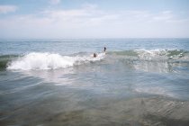 Мальчики, играющие в Waves у калифорнийского пляжа — стоковое фото