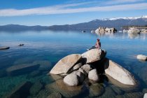 Jeune femme assise sur le rocher dans le lac tahoe sur l'après-midi ensoleillé — Photo de stock