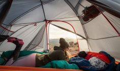 Mujer acampando en tienda de campaña en la montaña durante las vacaciones - foto de stock
