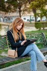Приваблива молода жінка дивиться на свій планшет у парку — стокове фото