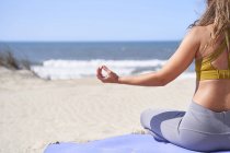 Close-up of young woman from behind making gesture of meditating with closed fingers in front of the sea. Relaxation, concentration and peace concept. — Stock Photo
