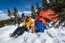 Giovane avventura maschile rendendo la cena accanto alla tenda in inverno — Foto stock
