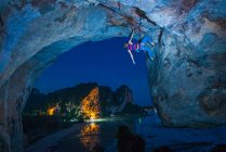 Giovanotto arrampicata strapiombante faccia di roccia a Tonsai spiaggia di notte — Foto stock