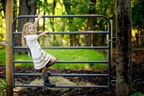 Menina loira escalando um portão na fazenda. — Fotografia de Stock