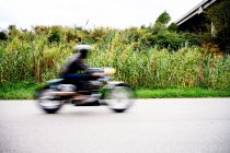 Вид сбоку на размытый винтажный мотоцикл на проселочной дороге — стоковое фото