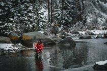 Жінка літає риболовлею, стоячи в річці взимку — стокове фото