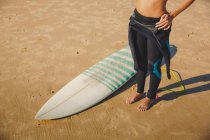 Top view of a surfer girl on the beach with her surfboard — Stock Photo