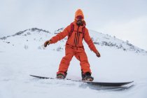 Улыбающийся человек катается на сноуборде на снежной горе в отпуске — стоковое фото