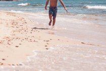 Parte inferior del cuerpo - chico corriendo en la playa. - foto de stock