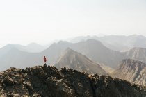 Жінка, дивлячись на погляд, стоячи на вершині гори на тлі чистого неба — стокове фото