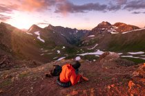 Senderista sentada en la montaña contra el cielo al atardecer - foto de stock