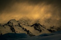 Szenische Aussicht auf schneebedeckte Berge gegen wolkenverhangenen Himmel bei Sonnenuntergang — Stockfoto
