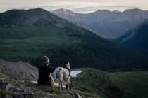 Женщина смотрит на горы во время похода с собакой во время отпуска — стоковое фото