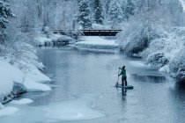 Vista posteriore della donna paddleboarding sul fiume durante l'inverno — Foto stock