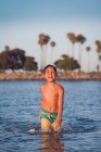 Молодий хлопчик у блакитній воді на пляжі — стокове фото