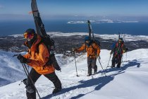 Homens com bastões de esqui escalando montanha coberta de neve durante as férias — Fotografia de Stock