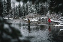 Uomo e donna a piedi nel fiume durante la pesca a mosca in inverno durante le vacanze — Foto stock