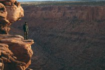 Uomo in piedi sul bordo della scogliera rocciosa a Canyonlands National Park — Foto stock