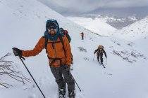 Люди с лыжными палками, сплитбордировавшие на снежной горе во время отпуска — стоковое фото