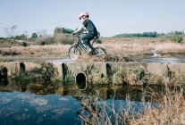 Jeune fille sur son vélo à travers une grande flaque d'eau éclaboussures — Photo de stock