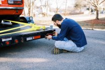 Millennial-Mechaniker in der Einfahrt repariert Rücklicht eines Autotransporters — Stockfoto