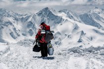 Rückansicht eines männlichen Wanderers, der im Urlaub auf schneebedeckten Bergen Taschen trägt — Stockfoto