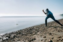 Homem skimming uma pedra no oceano em um dia ensolarado no Reino Unido — Fotografia de Stock