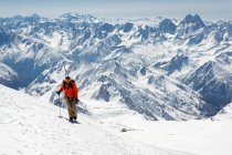 Человек с лыжной палкой, взбирающийся на снежную гору во время отпуска — стоковое фото