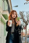 Жінка ходить, дивлячись на свій смартфон на вулиці — стокове фото