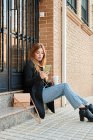Eine blonde Geschäftsfrau trinkt Kaffee und schaut auf ihr Handy — Stockfoto