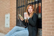 Блондинка-бизнесмен пьет кофе и смотрит в телефон — стоковое фото