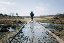 Hombre montando a través de un charco fangoso mientras ciclismo de montaña en Inglaterra - foto de stock