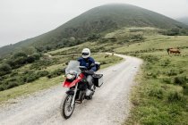 Biker man riding motorcycle in a mountain road — Stock Photo