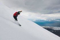 Homem snowboard na montanha coberta de neve contra o céu nublado durante as férias — Fotografia de Stock