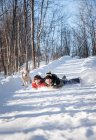 Pai e filho descendo uma colina nevada juntos no dia de inverno. — Fotografia de Stock