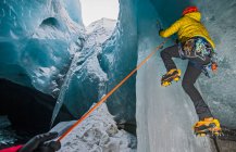 Uomo arrampicata ghiacciolo all'interno grotta ghiacciaio in Islanda — Foto stock