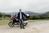 Man by  motorcycle  in mountains — Stock Photo