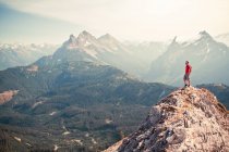 Man in red standing on summit looking out at the view. — Stock Photo