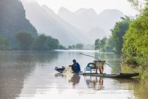Pescador en balsa tradicional en el río Yulong cerca de Yangshuo - foto de stock