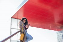 Una joven afroamericana feliz hablando con un celular en la ciudad - foto de stock
