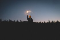 Menino iluminado por Sparkler fica na floresta no crepúsculo — Fotografia de Stock