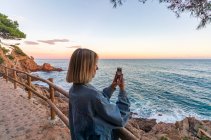 Jeune femme prenant des photos sur la plage — Photo de stock