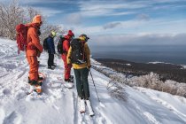 People in warm clothing with snowboards overlooking landscape against sky during vacation — Stock Photo