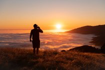 Silhouette of a man with a backpack on the top of the mountain — Stock Photo