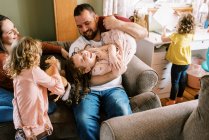 Happy young family of five laughing and playing together in home — Stock Photo